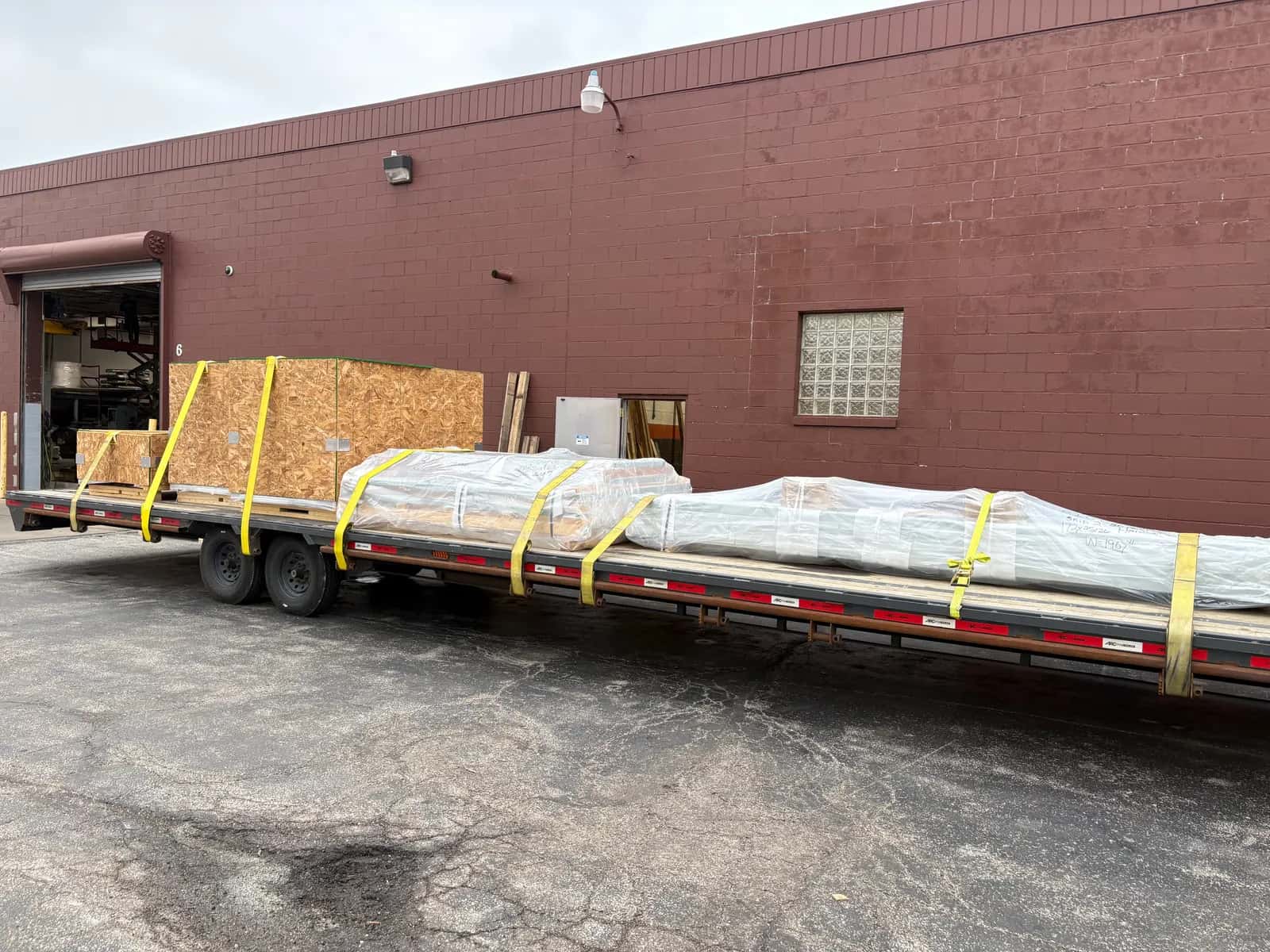 Crated and shrink-wrapped freight strapped on a deck at a loading dock