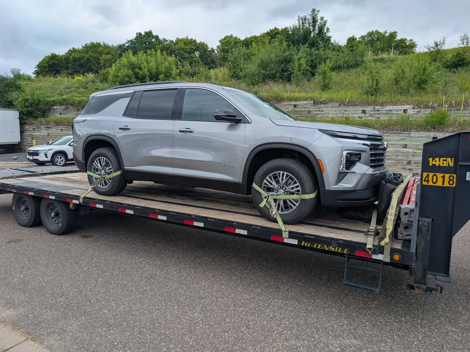 New SUV strapped to a gooseneck flatbed trailer for expedited transport