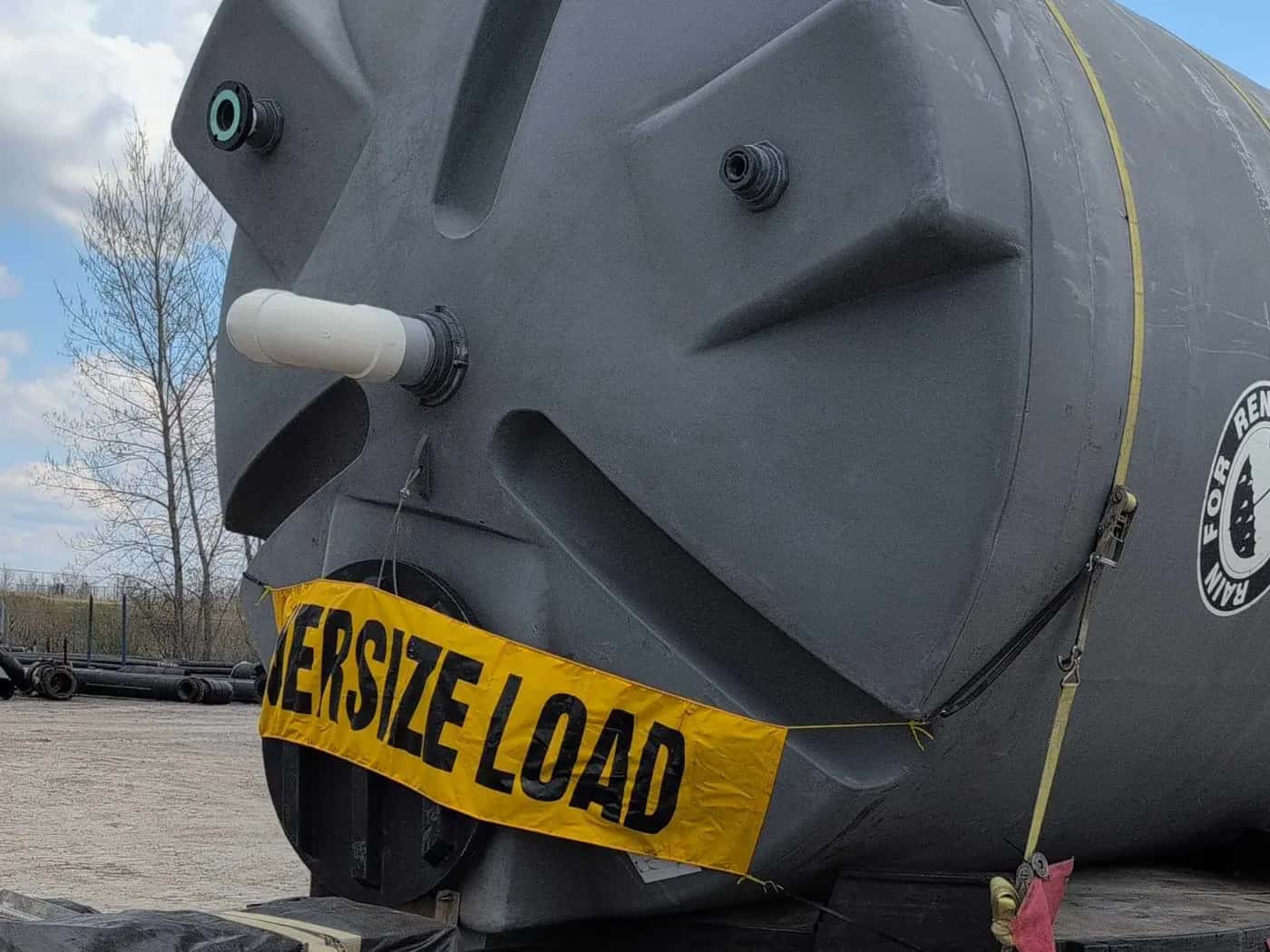 Oversize tank secured on a deck trailer with an OVERSIZE LOAD banner